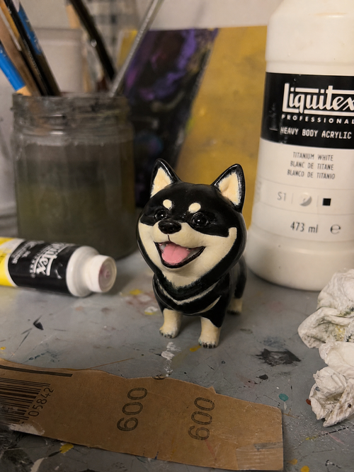 Hand-painted chibi black shiba figurine on the artisan workbench