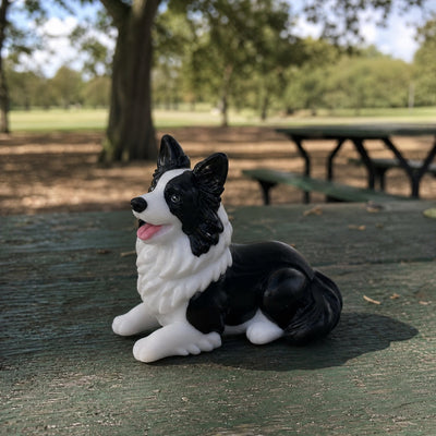 Hand-painted chibi figurine of the same border collie on a park table