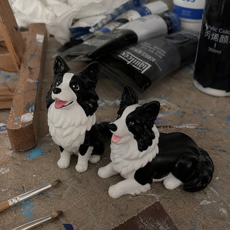 Hand-painted chibi figurines of the same border collie in the studio